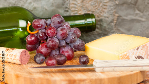 Rotweinflasche mit roten Trauben und Käse