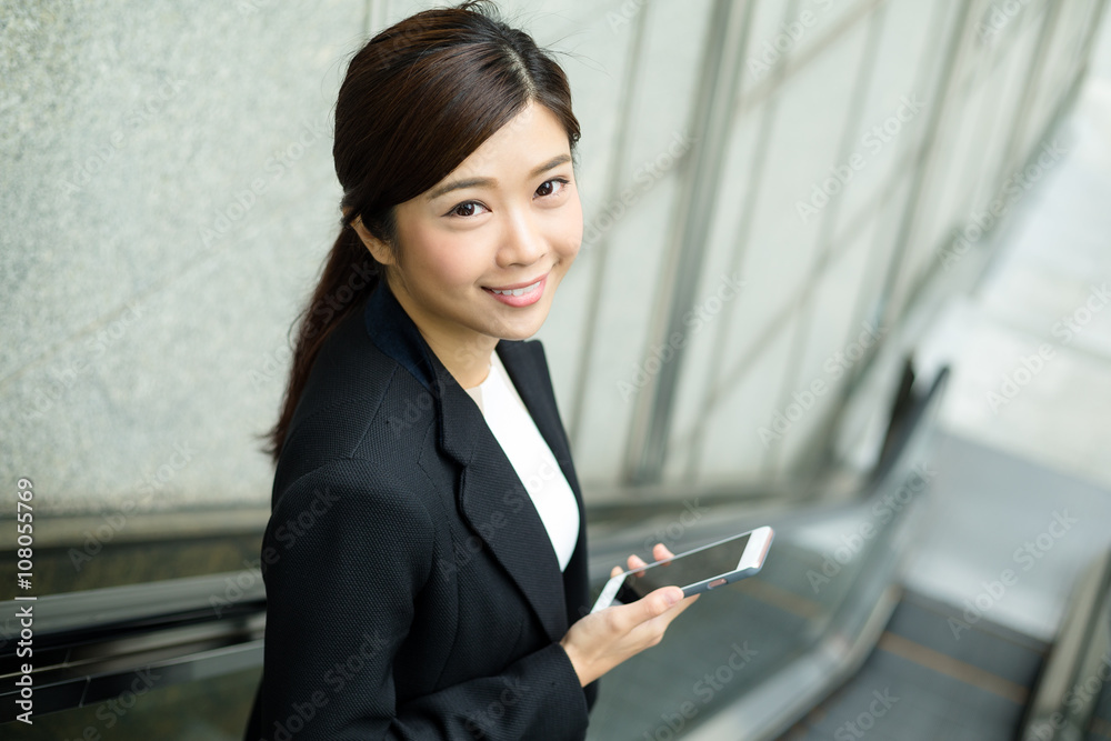 Business woman going down to escalator and hold with a cellphone Business woman going down to escalator and hold with a cellphone