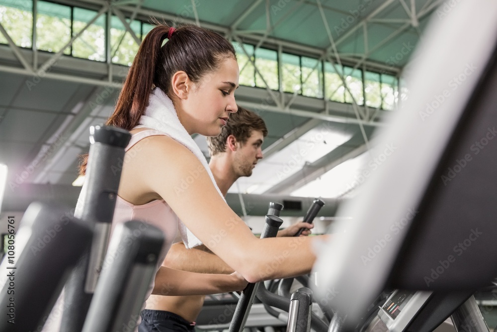 Woman and man exercising on the elliptical machine Woman and man exercising on the elliptical machine