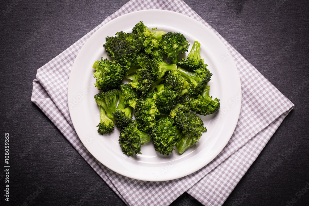 Bunch of fresh green broccoli on brown plate over wooden background Bunch of fresh green broccoli on brown plate over wooden background