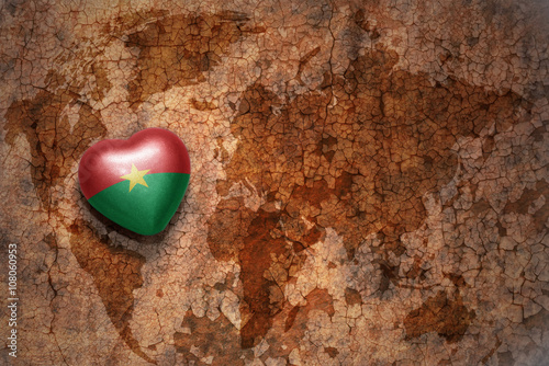 heart with national flag of burkina faso on a vintage world map crack paper background.