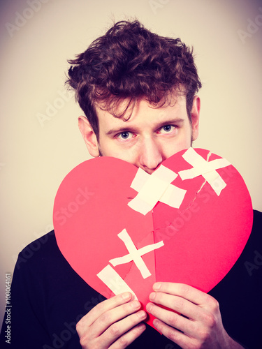 Sad man with glued heart by plaster. photo