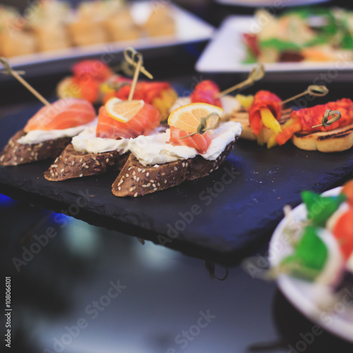 Beautifully decorated catering banquet table with different food snacks and appetizers with sandwich, caviar, fresh fruits on corporate christmas birthday party event or wedding celebration