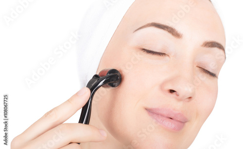 Photos Close up of woman using derma roller