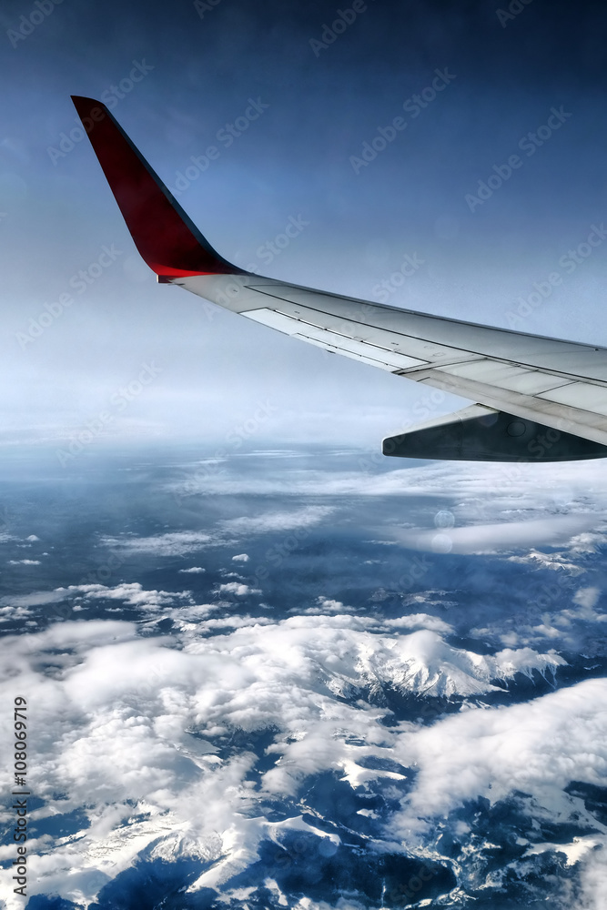 Wing of airplane above snowy mountains Wing of airplane above snowy mountains
