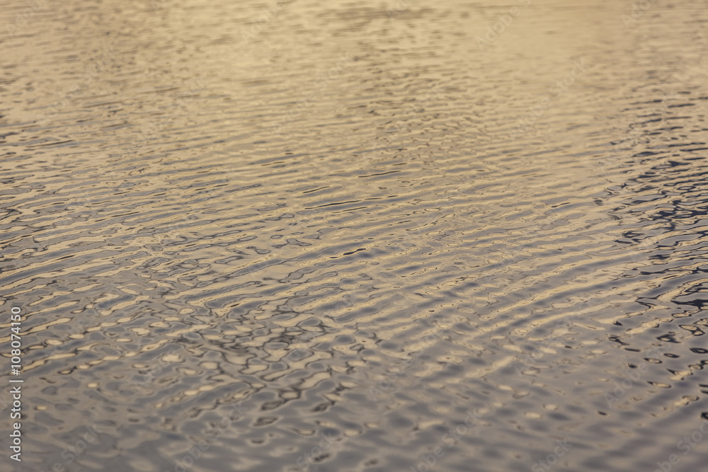 Ripples on the water at yellow sunrise background Ripples on the water at yellow sunrise background