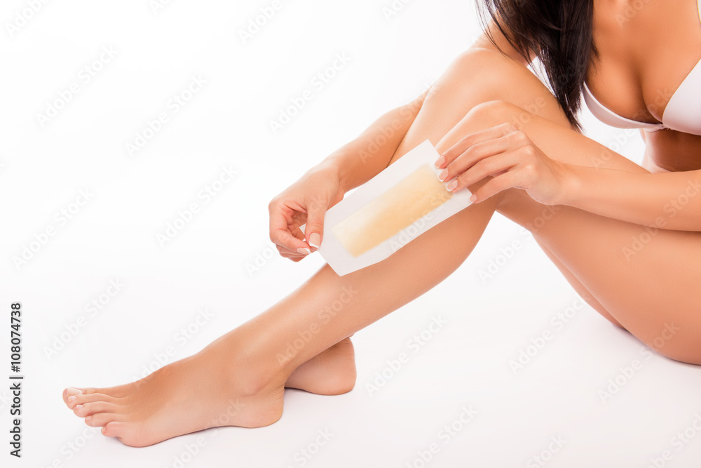Close up photo of woman using beeswax stripe to shave her leg