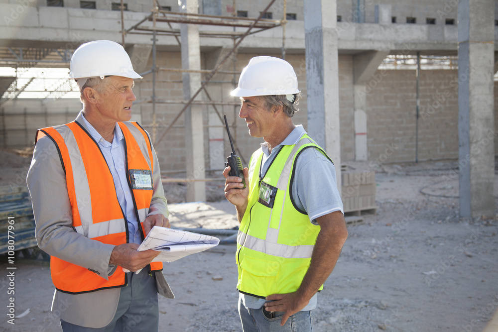 Caucasian architect and construction worker talking at construction site Caucasian architect and construction worker talking at construction site