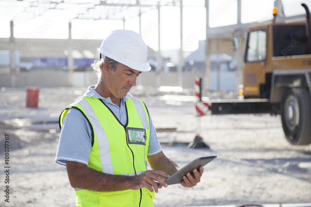 Caucasian construction worker using digital tablet at construction site Caucasian construction worker using digital tablet at construction site