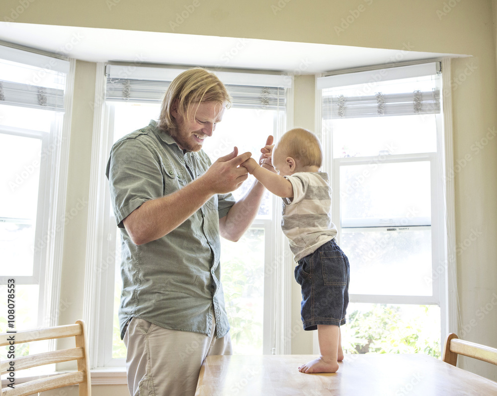 Caucasian father teaching son to stand on table Caucasian father teaching son to stand on table