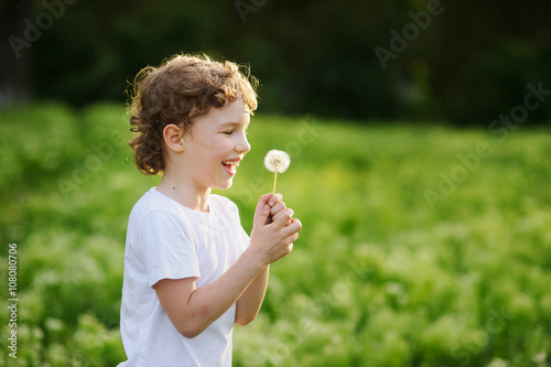 Child holding a dandelion and laughs