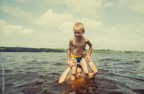 Caucasian father and son swimming in lake