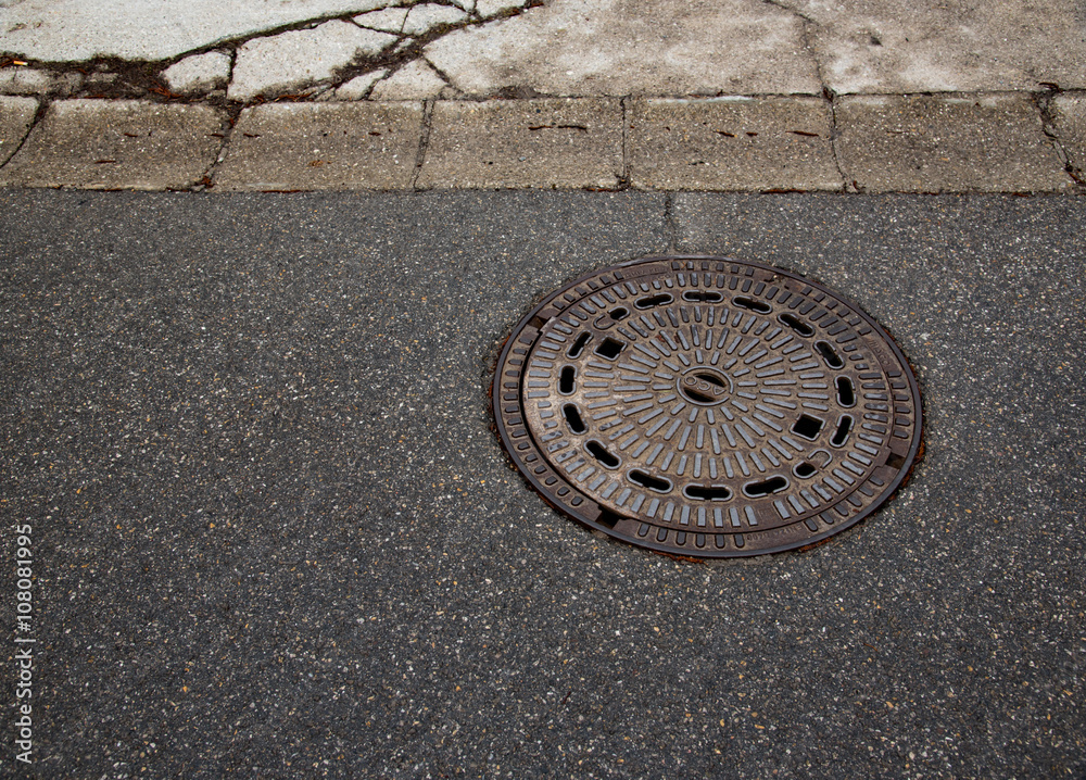 Abstract manhole cover on asphalt 