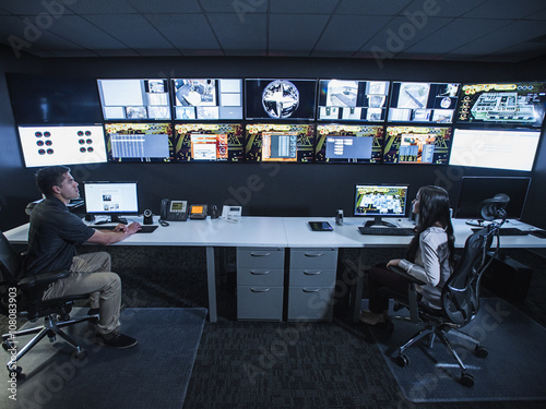 Security guards watching monitors in control room photo