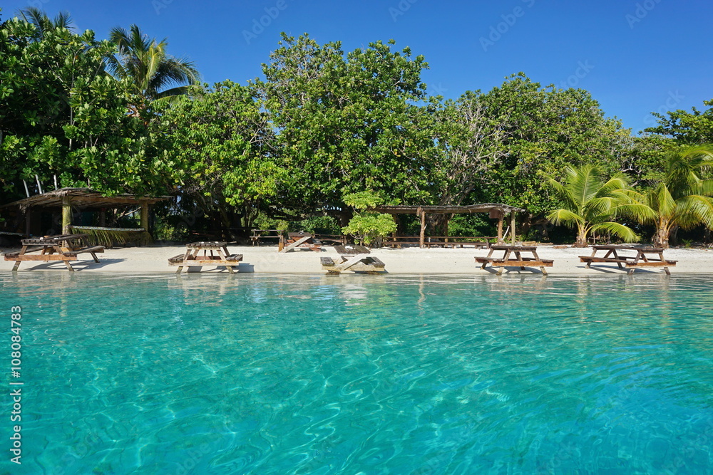 Picnic tables on a tropical beach with turquoise water on the shore of an islet, Huahine island, French Polynesia Picnic tables on a tropical beach with turquoise water on the shore of an islet, Huahine island, French Polynesia