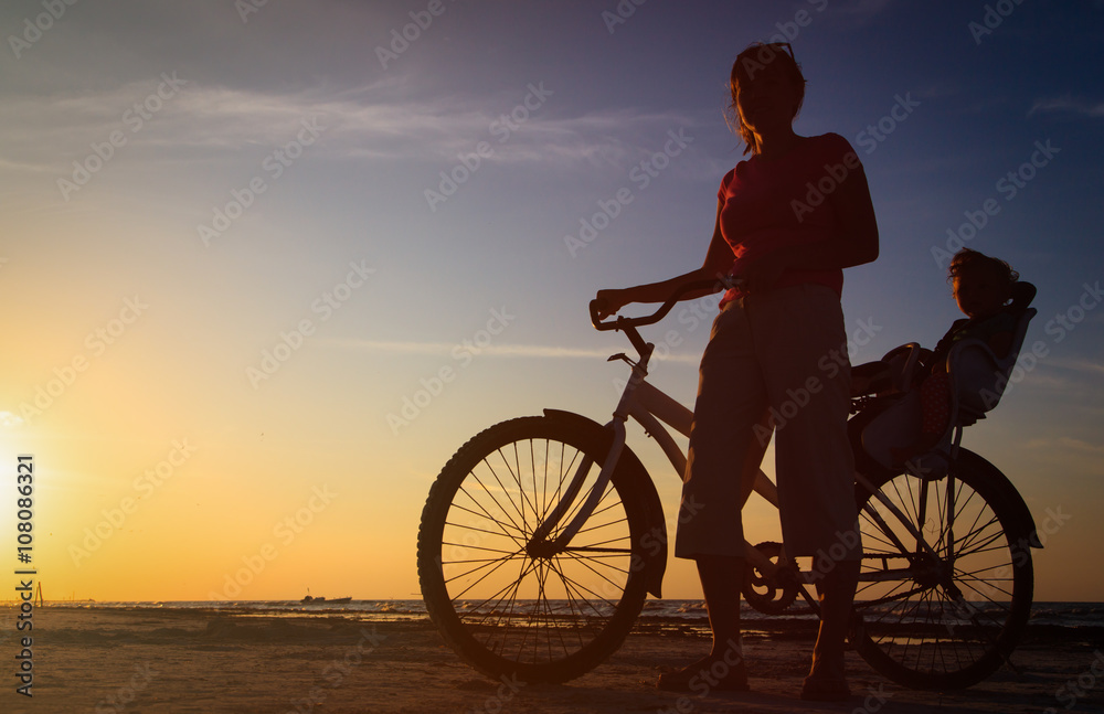 Fototapeta premium Silhouette of mother and baby biking at sunset
