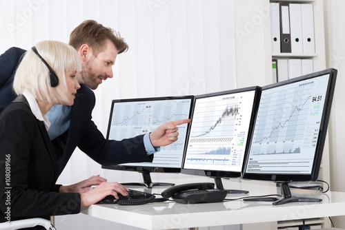 Businesspeople Analyzing Stock Charts On Multiple Computers