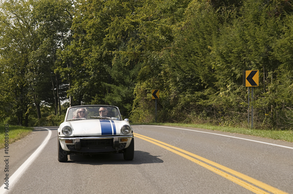 Couple driving convertible on rural road Couple driving convertible on rural road