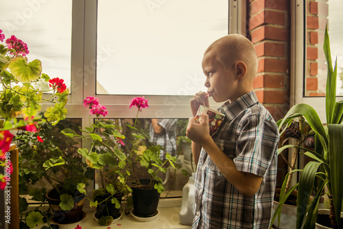 Caucasian boy drinking juice from mug by window photo