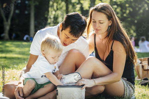 Family opening picnic lunch box in park