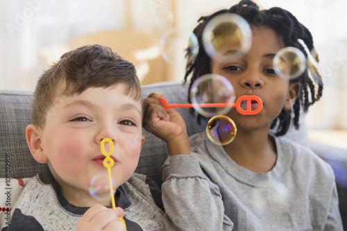 Close up of boys blowing bubbles on sofa