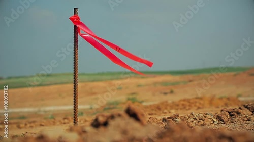 Metal survey peg with red flag on construction site.