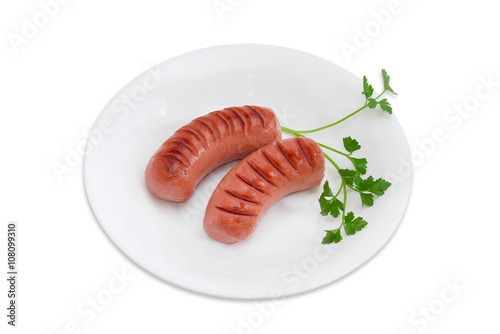 Canvas Print Grilled sausages and sprig of parsley on white dish