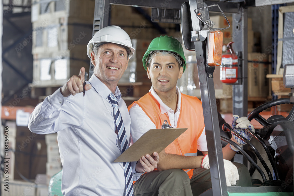Floor supervisor consulting with forklift operator Floor supervisor consulting with forklift operator