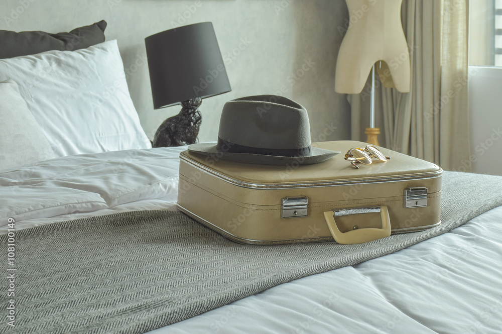 Φωτογραφία Retro style travel bag, hat and sunglasses on bed in hotel guestroom