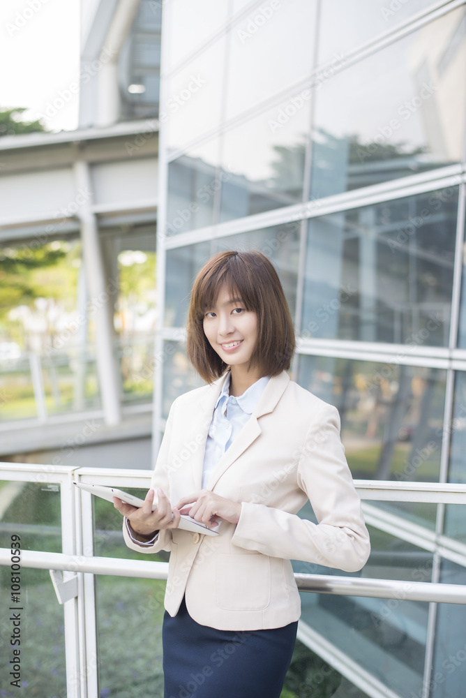 Attractive asian business woman working on tablet computer outsi Attractive asian business woman working on tablet computer outsi