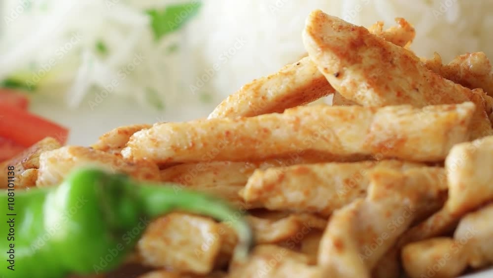 Grilled chicken rotating on plate with rice, green pepper, onion and tomatoes. Slow motion and close up shot. Grilled chicken rotating on plate with rice, green pepper, onion and tomatoes. Slow motion and close up shot.