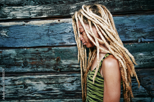 Woman with blonde dreadlocks at wooden wall photo