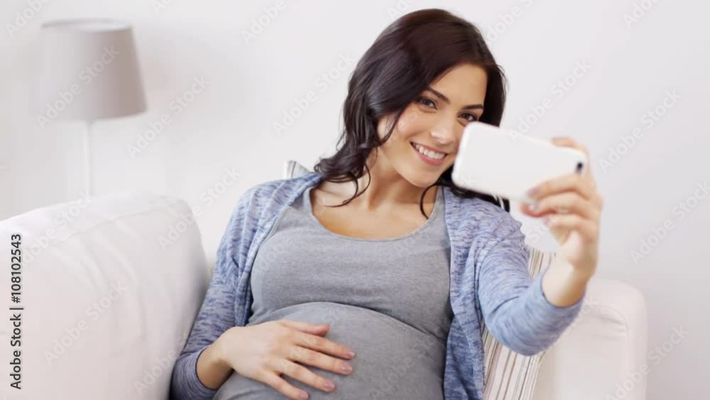 pregnant woman taking selfy by smartphone at home pregnant woman taking selfy by smartphone at home