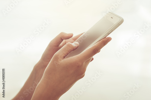 Young woman holding smarthphone in hand while typing