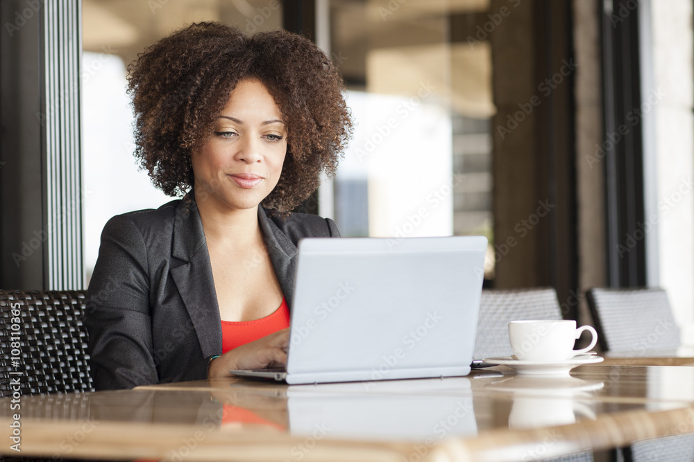 Mixed race businesswoman using laptop in cafe Mixed race businesswoman using laptop in cafe