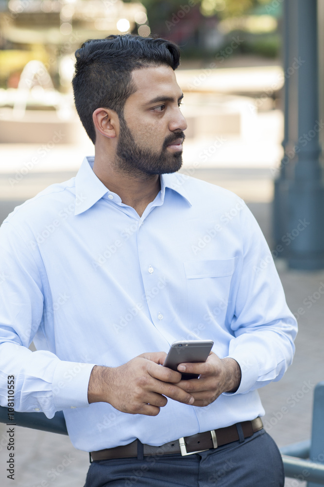 Indian businessman using cell phone in city Indian businessman using cell phone in city