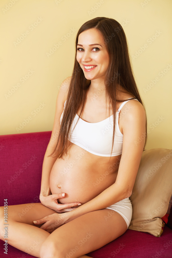 Lovely cheerful pregnant woman sitting on the sofa Lovely cheerful pregnant woman sitting on the sofa