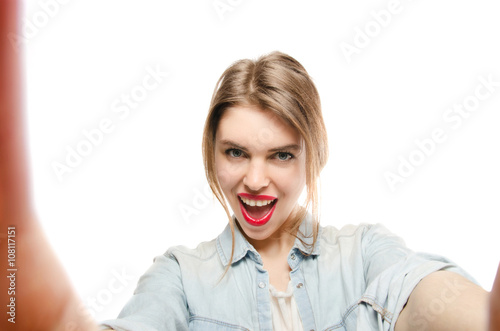 Closeup of beautiful playful woman making selfie photo on isolated white background and looking at camera