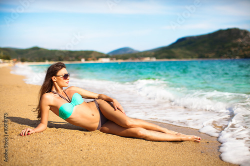 Pretty girl lying on a beach in a bikini and enjoying on sand by