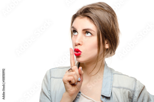 Portrait of young woman keeping finger on her lips and asking to keep quiet