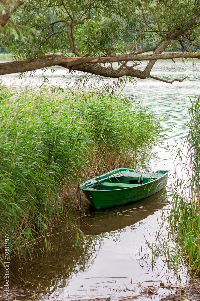A small rowing boat in reed by the lake shore. A small rowing boat in reed by the lake shore.