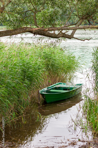 A small rowing boat in reed by the lake shore.