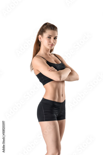 Cutout fitness woman in shorts and a tank top standing sideways with her arms folded
