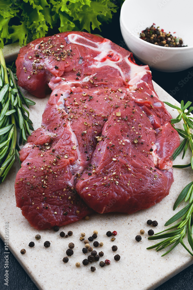 Fototapeta premium Beef, rosemary, pepper on chopping board of artificial stone