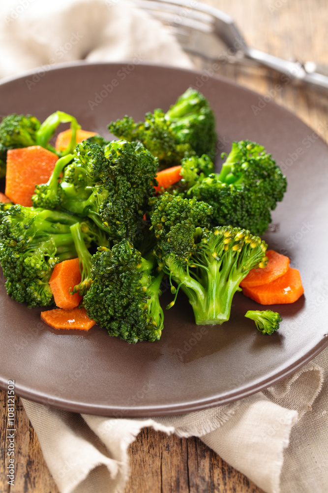 Closeup shot of steamed carrots and broccoli  on plate.