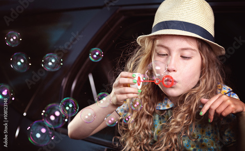 Blonde hair young girl lets soap bubbles in car