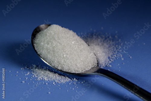 A spoon full of sugar on a blue background