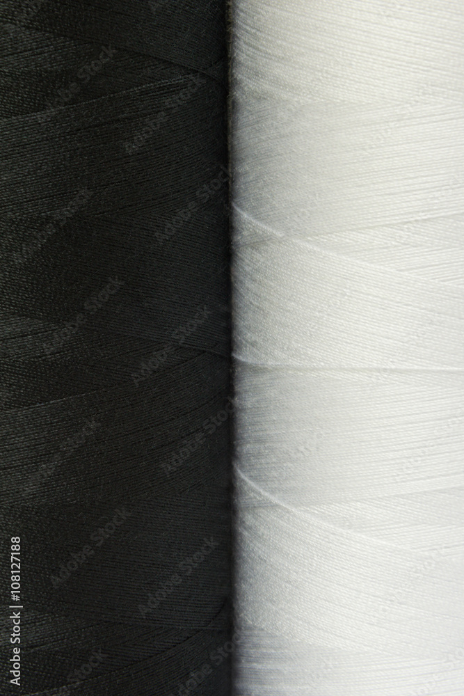 two black and white spools of thread close-up two black and white spools of thread close-up