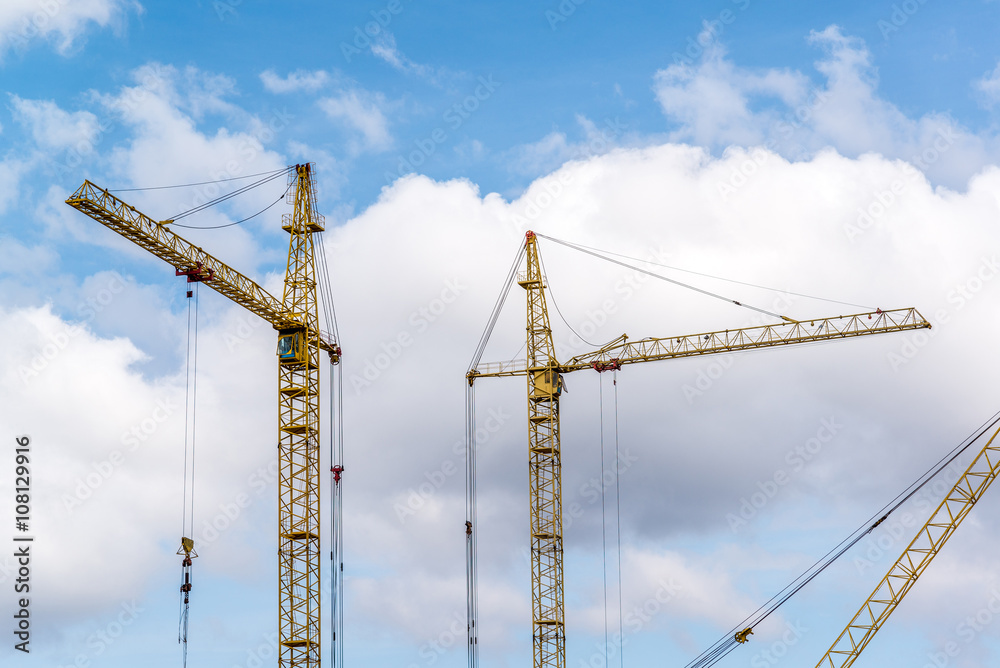 Two construction cranes on blue sky background Two construction cranes on blue sky background