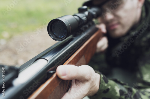 close up of soldier or hunter with gun in forest